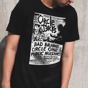 Pu&ograve; includere: Maglietta nera con una stampa bianca di un poster di un concerto che pubblicizza uno spettacolo con Bad Brains, Circle One e Circle Jerks. Il poster include la data, la posizione e le informazioni sui biglietti.