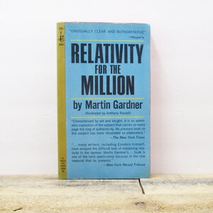 May include: A vintage paperback book titled "Relativity for the Million" by Martin Gardner. The book has a blue and yellow cover with white text. The book is standing on a light brown wooden surface.