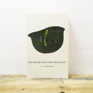 May include: A book cover with a green military helmet and the title "The River and the Gauntlet" by S.L.A. Marshall.