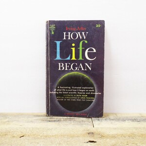 May include: A vintage paperback book titled "How Life Began" by Irving Adler. The cover features a dark blue background with a colorful illustration of a planet and the title in bold, colorful letters.