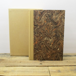 May include: Two books with brown and orange marbled covers. The book on the left has a plain brown cover. The book on the right has a marbled cover with brown, orange, and white swirls.