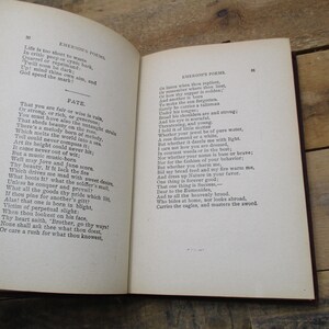 May include: An open book with yellowed pages, featuring a poem by Ralph Waldo Emerson titled "Fate". The text is printed in black ink on a white background. The book is bound in brown leather and has a worn, antique appearance.