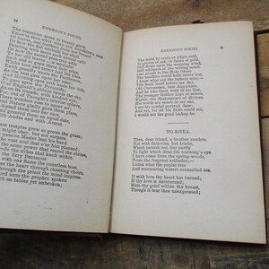 May include: An open book with yellowed pages, showing a poem by Ralph Waldo Emerson titled "To Kihla". The poem is printed in black ink on a white background. The book is bound in brown leather.