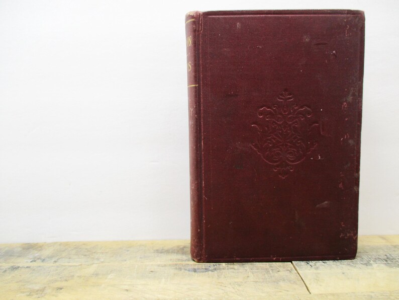 May include: A vintage, burgundy-colored hardcover book with gold lettering on the spine. The book has an ornate, embossed design on the front cover.