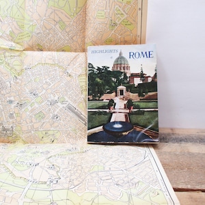 May include: A vintage travel guide to Rome, Italy, with a colorful illustration of a fountain and a building on the cover. The title reads "Highlights of Rome".