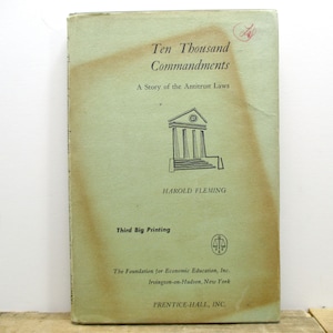 May include: A green book cover with the title "Ten Thousand Commandments: A Story of the Antitrust Laws" by Harold Fleming. The book is a third printing and published by Prentice-Hall, Inc.