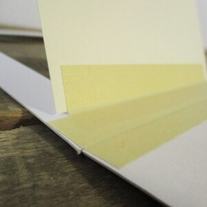 May include: A close-up of a white mat with two strips of yellow tape attached to the edge.