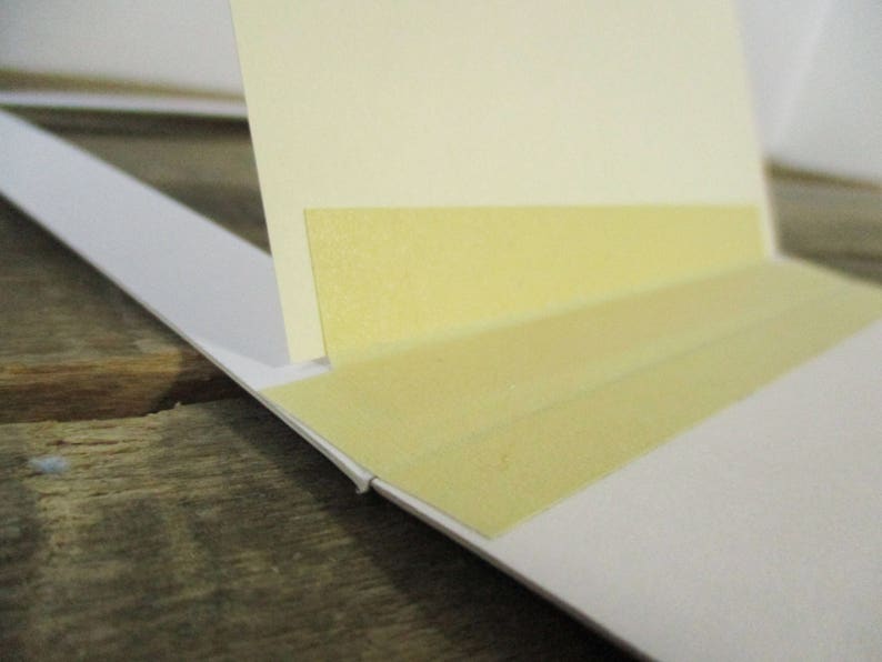 May include: A close-up of a white mat with two strips of yellow tape attached to the edge.