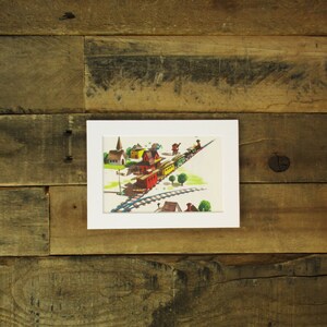May include: A framed illustration of a train traveling through a small town. The train is made up of a red engine, yellow boxcars, and green passenger cars. The town has a church, houses, and trees.