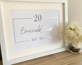 Peut inclure: Une impression encadrée blanche avec une inscription argentée qui lit "20 Emerald View EST 2018".