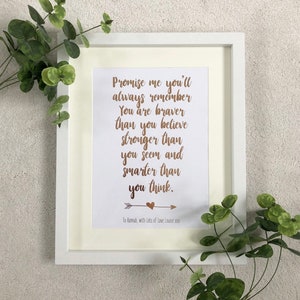 Op de afbeelding: Een ingelijste print met een witte rand en een crèmekleurige passe-partout. De print heeft goudkleurig schrift met de tekst "Promise me you'll always remember..." met een hart- en pijldesign. De tekst is gericht aan "To Hannah, with Lots of Love Louise xxx".