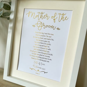 以下が含まれることがあります： 「Mother of the Groom」の金色の文字が書かれた額入りのプリント。感謝の詩が書かれており、「Rebecca XX」と日付が署名されています。フレームは白で、クリーム色のマットが付いています。