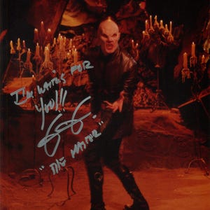 May include: A signed photograph featuring a bald, pale-skinned figure in a black leather outfit, with the text "I'm waiting for you!!!" and "The Master". The background includes candles and a dimly lit, reddish environment.