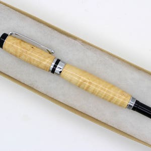 May include: A wooden pen with black and silver trim. The pen is in a brown box with white tissue paper.
