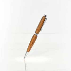 May include: A brown wooden pen with silver accents. The pen has a twist-top mechanism and a smooth, polished finish.