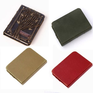 May include: Four rectangular notebooks with rounded corners. One is dark brown with a raised tree relief and the name KERRY embossed on a plaque. The other three are solid, plain covers in matte olive green, muted gold, and bright red colors.