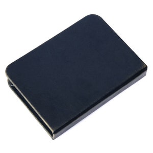 May include: A rectangular, dark navy blue wallet with rounded corners. The wallet is closed and features a smooth, solid-colored exterior surface. It is positioned at an angle, showing the top cover and the side edge of the folded item.