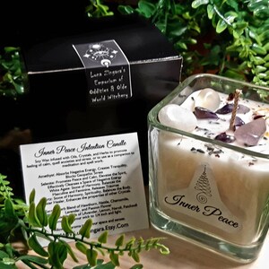 Pode incluir: Um frasco de vela quadrado de vidro com uma vela branca e cristais dentro. A vela &eacute; etiquetada como "Inner Peace" e est&aacute; cercada por vegeta&ccedil;&atilde;o. O frasco est&aacute; sobre uma superf&iacute;cie de madeira. A vela &eacute; feita com cera de soja, cristais e ervas para promover uma sensa&ccedil;&atilde;o de calma, medita&ccedil;&atilde;o tranquila e al&iacute;vio do estresse.