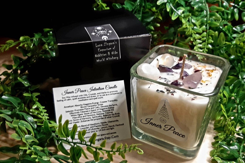 Pode incluir: Um frasco de vela quadrado de vidro com uma vela branca e cristais dentro. A vela &eacute; etiquetada como "Inner Peace" e est&aacute; cercada por vegeta&ccedil;&atilde;o. O frasco est&aacute; sobre uma superf&iacute;cie de madeira. A vela &eacute; feita com cera de soja, cristais e ervas para promover uma sensa&ccedil;&atilde;o de calma, medita&ccedil;&atilde;o tranquila e al&iacute;vio do estresse.