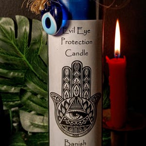 May include: Blue candle with a white label that says "Evil Eye Protection Candle" and features a black and white image of the Hamsa hand. The label also says "Banish And Protect". A blue evil eye charm is attached to the top of the candle.