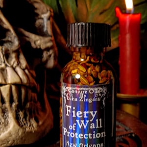 May include: A small glass bottle with a black cap filled with a brown liquid and herbs. The label reads "Conjure Oils by Luha Zingara Fiery Wall Protection New Orleans Hoodoo Oils Curiously Crafted Cauldron Creations".