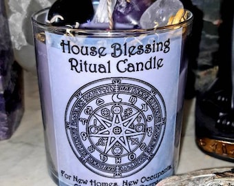 May include: A purple and white candle with a black and white sigil design. The candle is labeled "House Blessing Ritual Candle" and "For New Homes, New Occupants, Old Ghosts, Bad Energy".