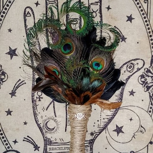May include: A peacock feather bouquet with brown feathers and a twine-wrapped handle. The bouquet is in front of a beige background with a black and white illustration of a hand with a palmistry chart and the words "Palmistry Fortune Telling".