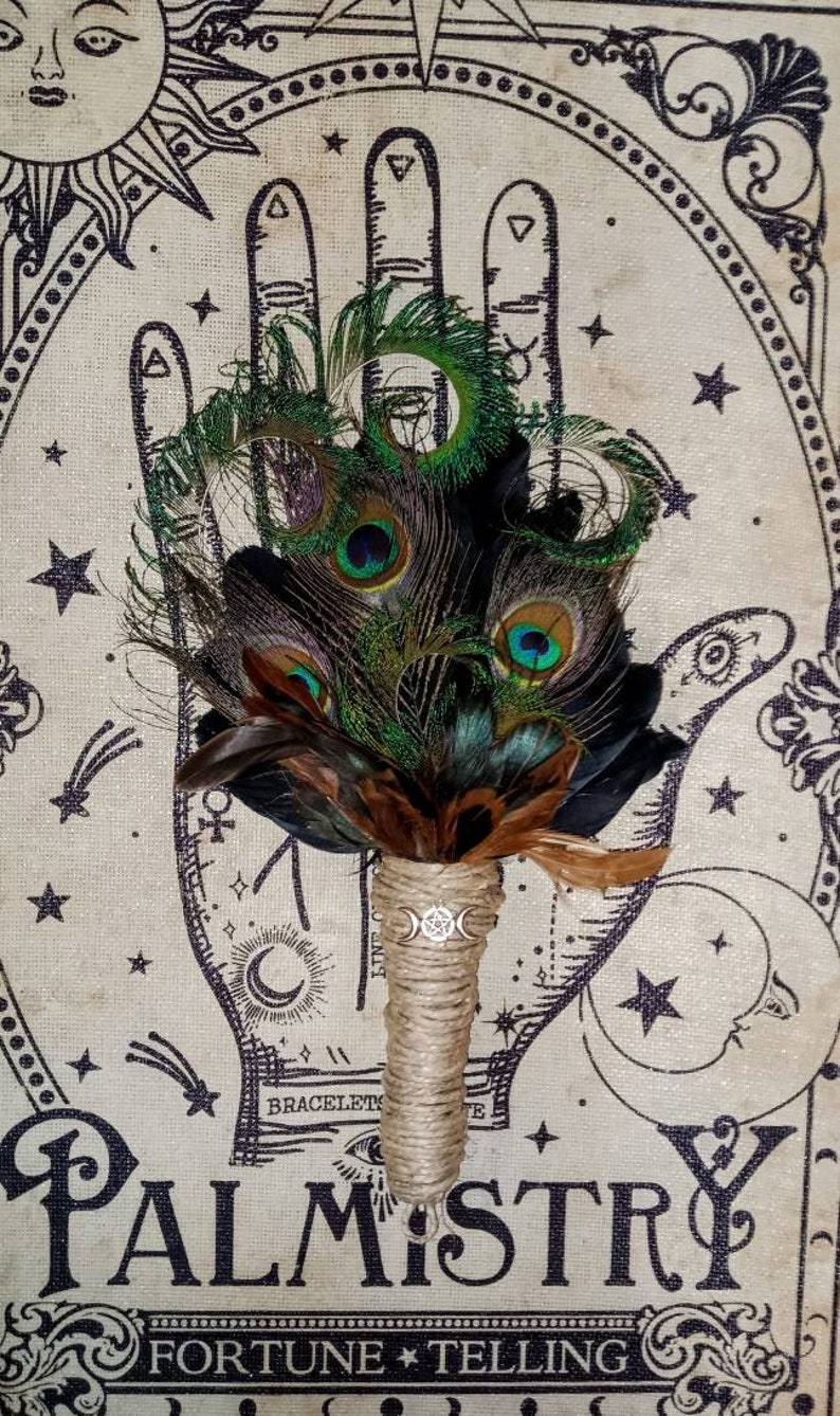 May include: A peacock feather bouquet with brown feathers and a twine-wrapped handle. The bouquet is in front of a beige background with a black and white illustration of a hand with a palmistry chart and the words "Palmistry Fortune Telling".