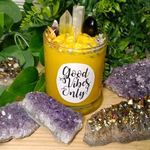 May include: A yellow candle with a label that reads "Good Vibes Only!" surrounded by amethyst and gold crystals.