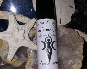 May include: A white roll-on bottle with a black cap. The label reads "Luna Zingara Perfume Oil Goddess Collection Amphitrite Waves". The bottle is sitting on a white and brown surface.
