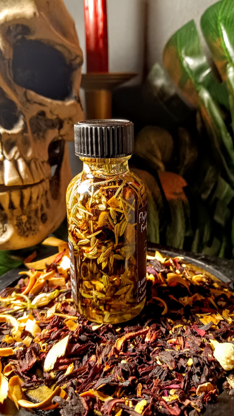 May include: A small glass bottle with a black lid filled with a yellow liquid and herbs. The bottle is sitting on a bed of dried flowers and herbs.