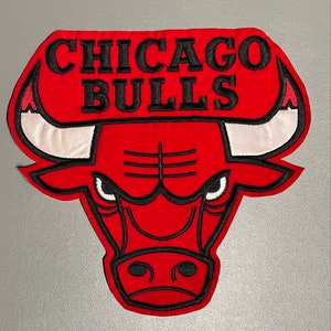 May include: Embroidered patch featuring the Chicago Bulls logo. The patch is red with black and white accents, including the team name and a bull's head. The design is detailed with black stitching.