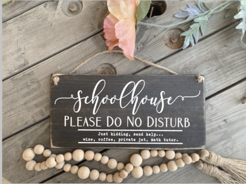 May include: A black wooden sign with white text that reads "Schoolhouse Please Do No Disturb" and "Just kidding, send help... wine, coffee, private jet, math tutor."