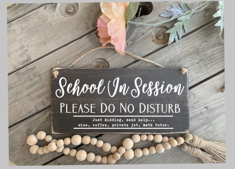 May include: A black wooden sign with white text that reads "School In Session PLEASE DO NO DISTURB Just kidding, send help... wine, coffee, private jet, math tutor."