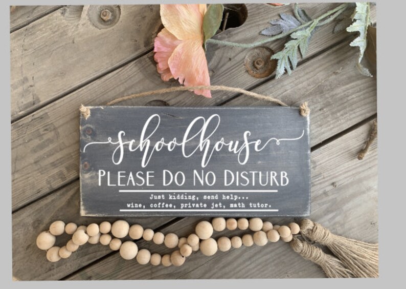 May include: A black wooden sign with white text that reads "Schoolhouse Please Do No Disturb" and "Just kidding, send help... wine, coffee, private jet, math tutor."