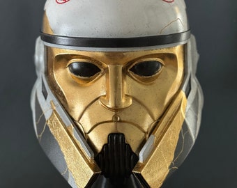 May include: A gold and white helmet with a black visor and red star symbols. The helmet is cracked and weathered, giving it a distressed look.