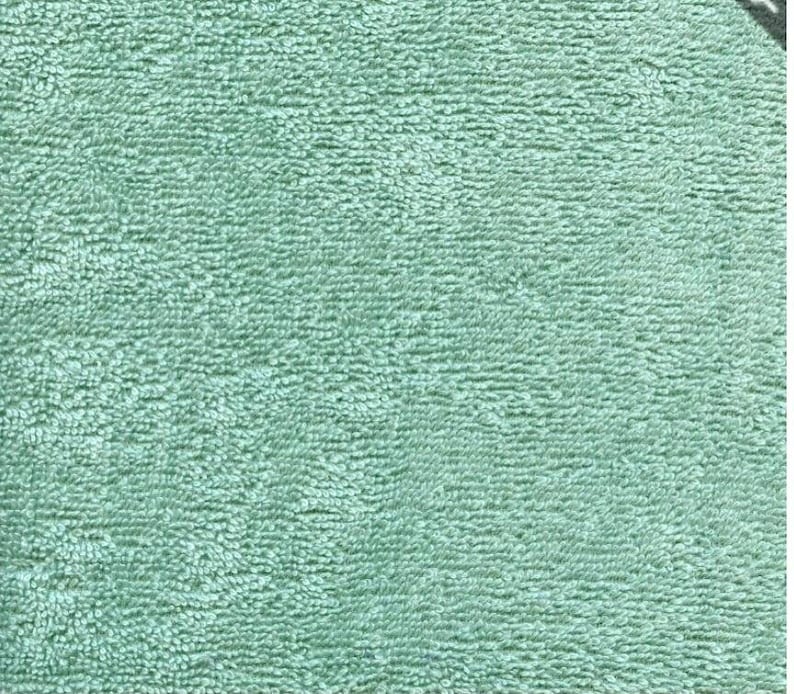 May include: A close-up of a soft, light blue, textured fabric. The fabric has a fuzzy, looped texture.