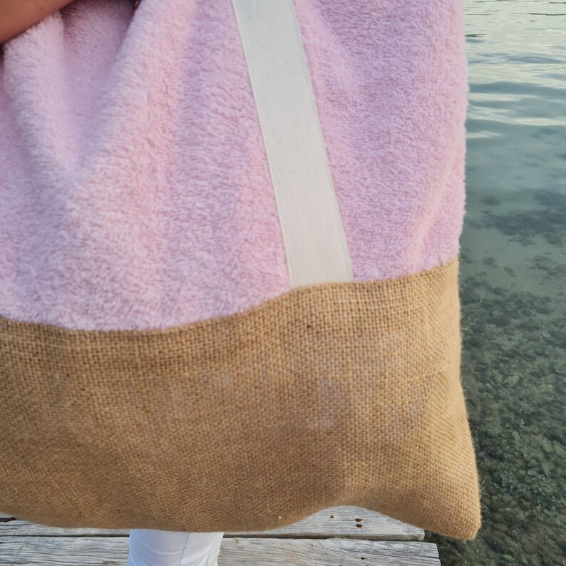 May include: A pink and brown tote bag with a white strap. The bag is made of a soft, fuzzy material and has a burlap bottom.
