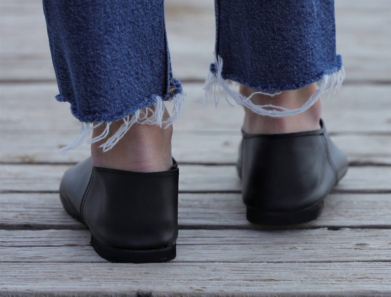 May include: A pair of black leather slip-on shoes with frayed denim jeans.