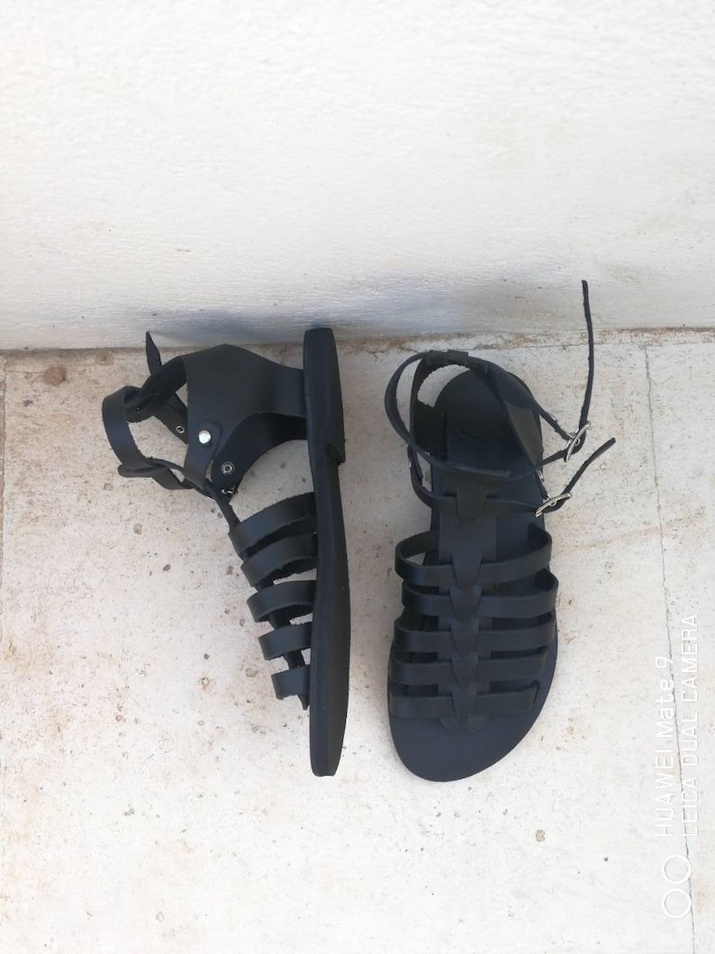 May include: A pair of black leather gladiator sandals with a criss-cross strap design.