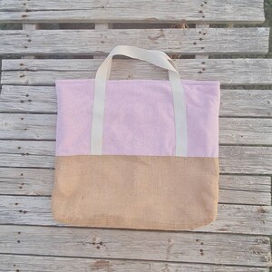 May include: A pink and brown tote bag with white straps. The bag is made of a soft, fuzzy material on the top half and a woven material on the bottom half.