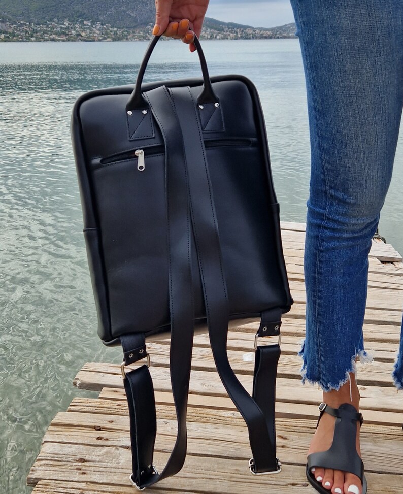 May include: A black leather backpack with adjustable straps and a zippered pocket on the front.