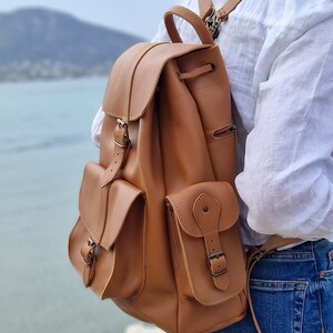 Puede incluir: Una mochila de cuero marr&oacute;n con correas ajustables, dos bolsillos delanteros con hebillas y cierre de cord&oacute;n.