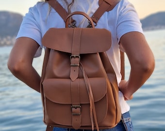 May include: A brown leather backpack with a flap closure and adjustable straps. The backpack has a front pocket and a drawstring closure.