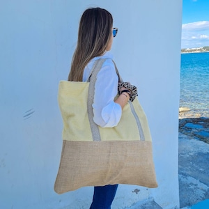 May include: A large, yellow and brown tote bag with black and white striped handles. The bag is made of a woven material and has a  fabric top.