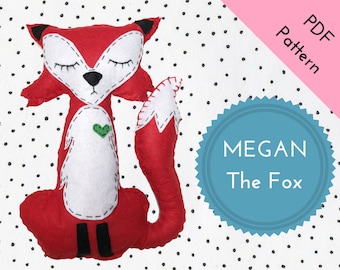 May include: A red felt fox plush toy with white felt accents and black felt eyes. The fox has a green felt heart on its chest and the text "MEGAN The Fox" is on a blue circle with a white border.