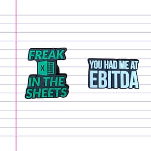 May include: Two black and green shoe charms with white text. One charm says "FREAK IN THE SHEETS" with an Excel spreadsheet icon. The other charm says "YOU HAD ME AT EBITDA" in a black rectangle with a light blue border.