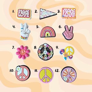 May include: A selection of colourful shoe charms featuring peace and love motifs. Designs include a peace sign, a rainbow, a flower, and the peace hand symbol. The charms are in various colours, including pink, yellow, and blue.