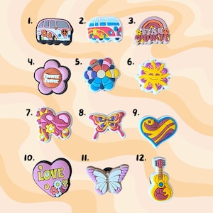 May include: A selection of colourful shoe charms featuring diverse designs. These include a flower power van, a rainbow with "Stay Groovy" text, a flower, a sun, a butterfly, a heart, a guitar, and other designs.