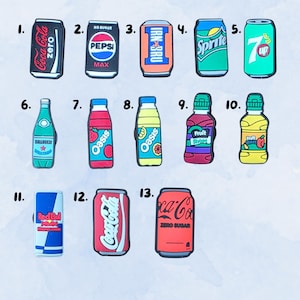 May include: A collection of thirteen colourful shoe charms shaped like various beverage cans and bottles, including Coca-Cola, Pepsi, Irn-Bru, Sprite, 7-Up, Oasis, Fruit Shoot, and Red Bull, each numbered from one to thirteen for identification.
